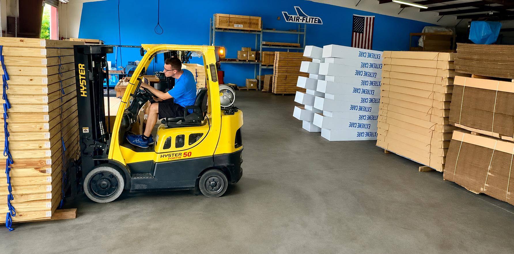 Air-Flite warehouse forklift handling stacked air trays and shipping containers